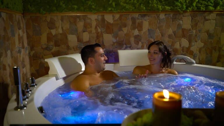 Couple relaxing in a warm, bubbling hot tub by candlelight