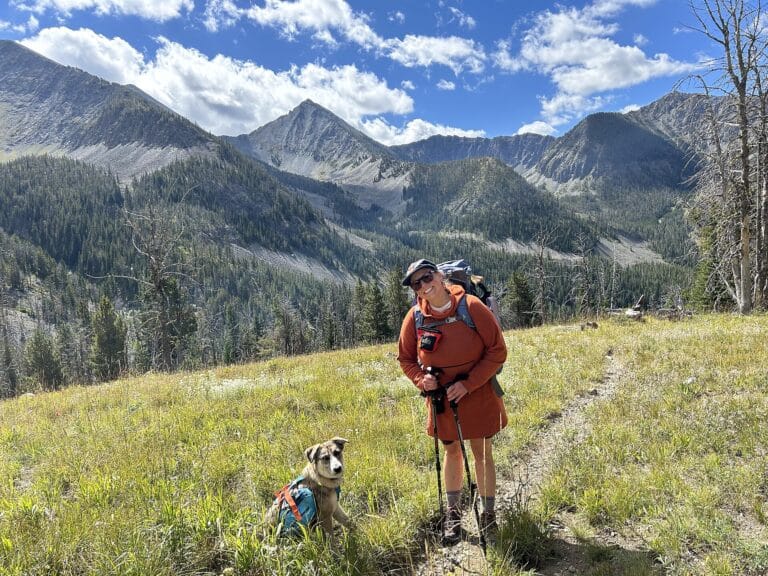 Hiker and her dog pausing on a forest trail